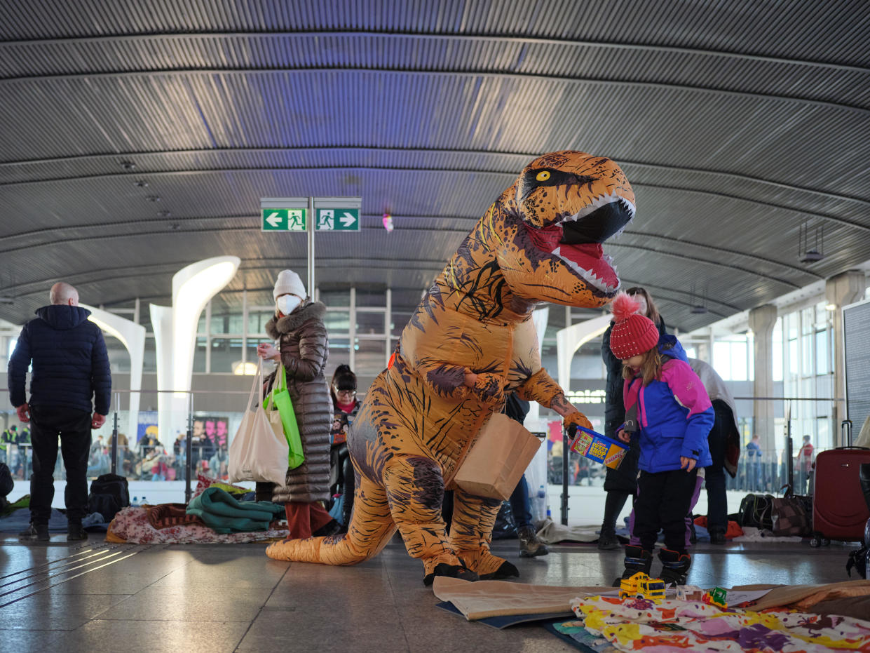 Tomasz Grzywiński suits up in a Tyrannosaurus rex costume and heads down to the Warsaw Central Train station with a bucket of candy and other goodies.  / Credit: Adam Zapala