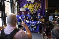 Cheerleders for the The Minnesota Vikings NFL team pose for pictures with supporters of the team at a fan interaction event at The Brotherhood Of Pursuits And Pastimes sports bar in Manchester, England, Wednesday, Sept. 28, 2022. A half-dozen NFL teams are aggressively targeting fans in Britain now that they have new marketing rights in the country. They’re signing commercial deals and hiring local media personalities in bids to expand their fanbases and tap international revenue. (AP Photo/Jon Super)