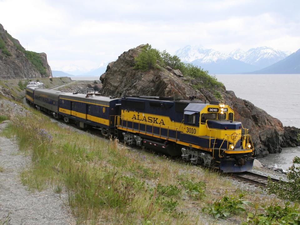 Yellow and black Alaska railway going through rocky pass with mountain views