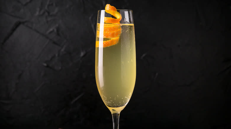 Close-up of a French 75 cocktail in a flute glass on a black background