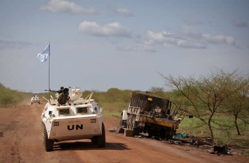 United Nations Mission in Sudan (UNMIS) peacekeepers drive past a destroyed UN truck that was part of a UN convoy ambushed in May 2011 while transporting northern soldiers out of Abyei as part of an agreement between the north and the south to help demilitarise and reduce tension in the area