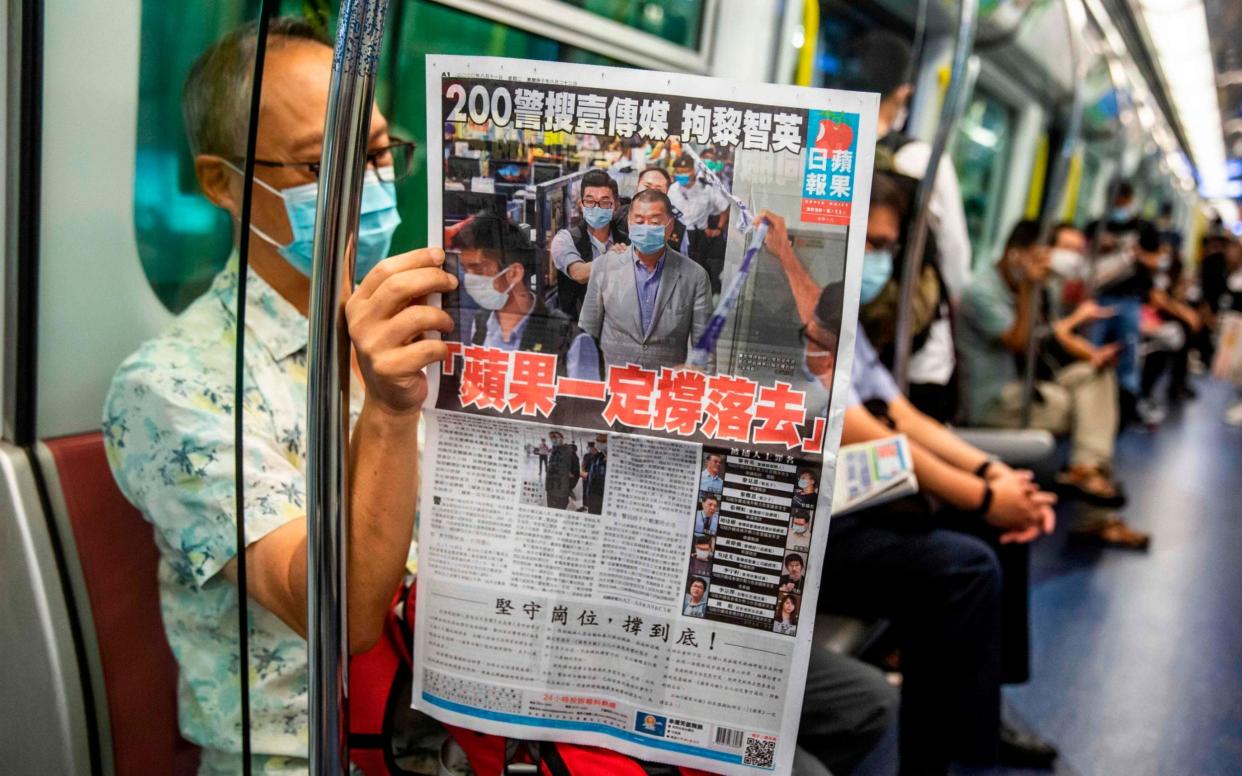 A commuter reads a copy of the Apple Daily newspaper  - ISAAC LAWRENCE/AFP via Getty Images