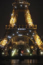 Media stand in front of the Eiffel Tower where the word "Merci", the French word for 'Thank you", is emblazoned as France's coronavirus death toll continued to climb, in Paris, Friday, March 27, 2020. Health workers fighting to save lives in France from COVID-19 have received a huge show of gratitude, from the Eiffel Tower. The new coronavirus causes mild or moderate symptoms for most people, but for some, especially older adults and people with existing health problems, it can cause more severe illness or death. (AP Photo/Thibault Camus)