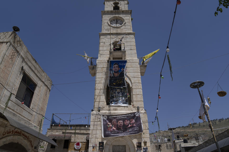 Posters showing militants from the Lions' Den group who were killed by Israeli forces hang from the historical clock tower in the Old City of Nablus, in the West Bank, Thursday, May 4, 2023. The killing of Zuhair al-Ghaleeth last month, the first slaying of a suspected Israeli intelligence collaborator in the West Bank in nearly two decades, has laid bare the weakness of the Palestinian Authority and the strains that a recent surge in violence with Israel is beginning to exert within Palestinian communities. (AP Photo/Nasser Nasser)