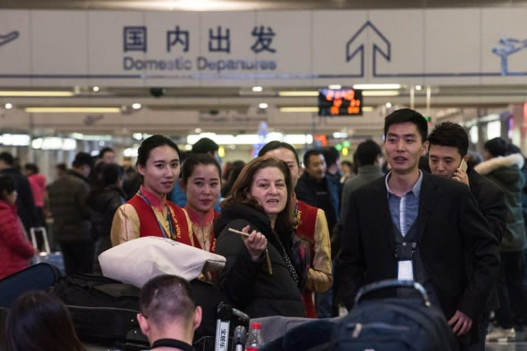 Ursula Gauthier (L), the Beijing-based correspondent for French news magazine L'Obs, speakes with hostesses at the airport before she takes her flight back to France, in Beijing on December 31, 2015