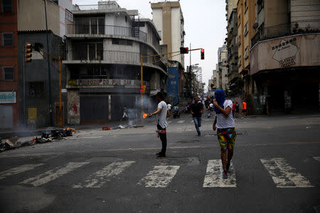 A demonstrator holds a burning object at a protest against the government of Venezuelan President Nicolas Maduro in Caracas, Venezuela March 31, 2019. REUTERS/Carlos Garcia Rawlins