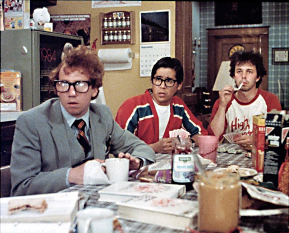 A group of men in glasses sit at a crowded table