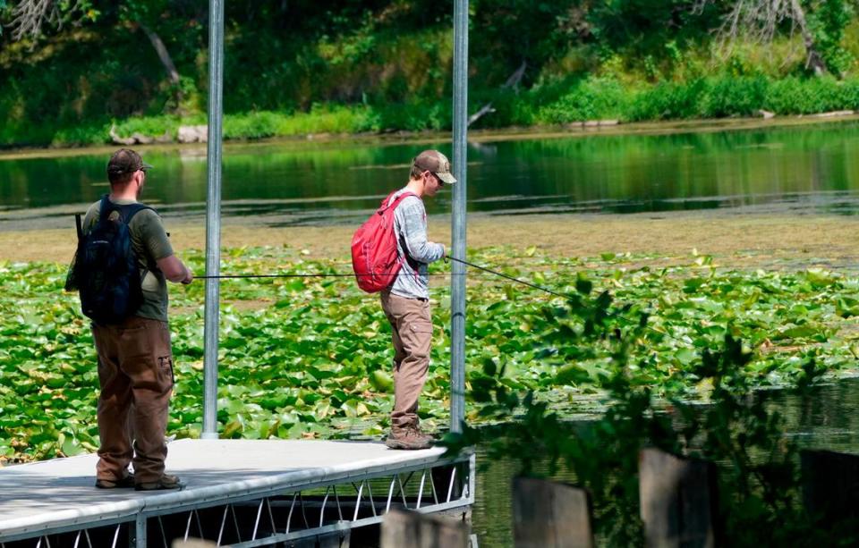 Josh White (left) and his son Ethan try their luck fishing off a pier on Third Lake in western Trempealeau, Wisconsin on Aug. 25, 2023.