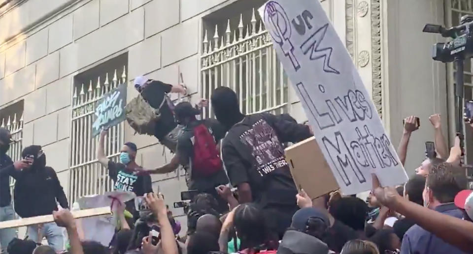 Protesters surround a man who is seen spray-painting a wall in front of the White House.