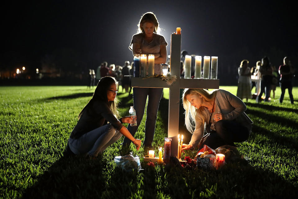 <p>Maria Reyes, Stacy Buehler and Tiffany Goldberg light candles around a cross as they attend a candlelight memorial service for the victims of the shooting at Marjory Stoneman Douglas High School that killed 17 people on Feb. 15, 2018 in Parkland, Fla. (Photo: Joe Raedle/Getty Images) </p>