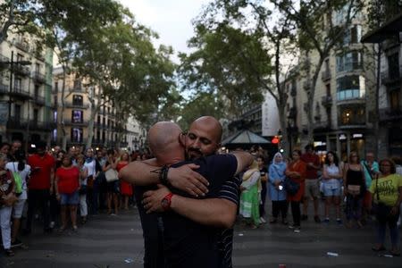 A Muslim man gives hugs next to a sign reading "I am Muslim, I am not a terrorist. I share hugs of love and peace" (not pictured), at where a van crashed into pedestrians at Las Ramblas in Barcelona, Spain, August 20, 2017. REUTERS/Susana Vera