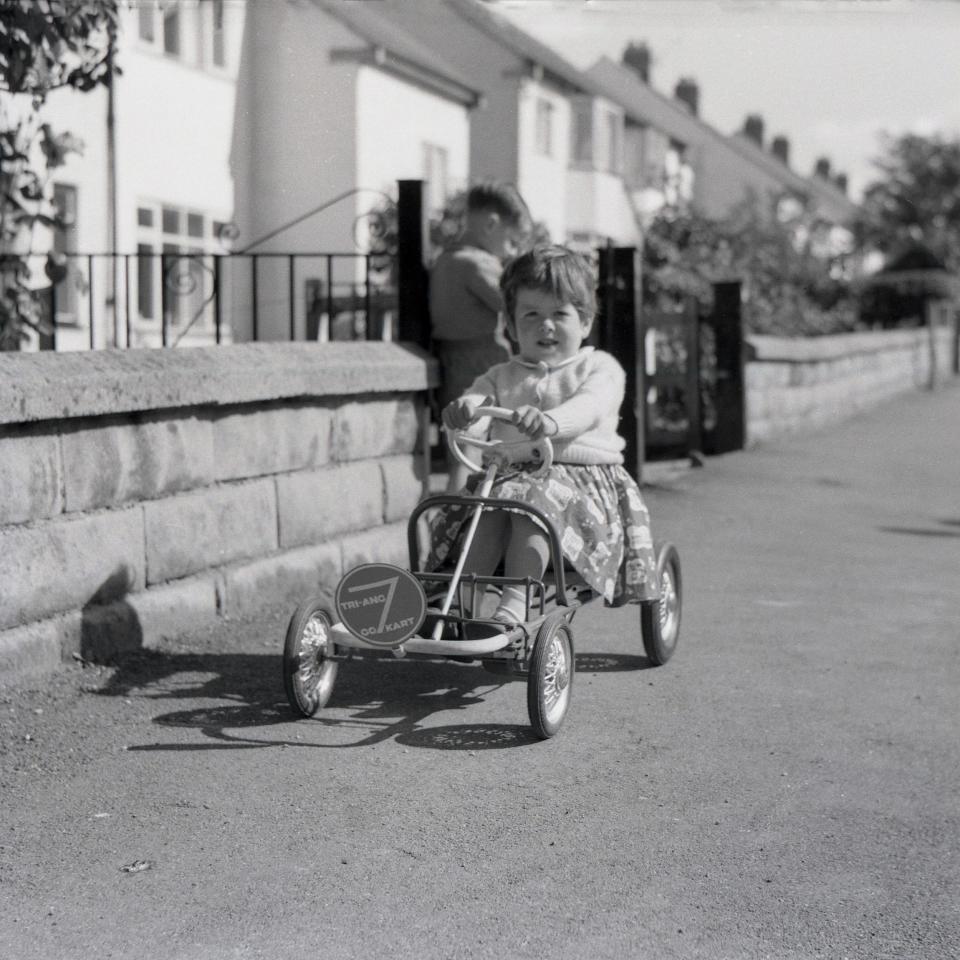 A young girl sitting on a metal framed Tri-Ang 7 Go Kart