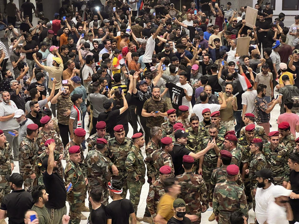 Iraqi protesters breach Baghdad's parliament in Baghdad, Iraq, Wednesday, July. 27, 2022. The majority of the protesters were followers of influential Shiite cleric Muqtada al-Sadr. The demonstrators, all of them men, were seen walking on tables of the parliament floor, sitting in the chairs of lawmakers and waving Iraqi flags. (AP Photo/Ali Abdul Hassan)