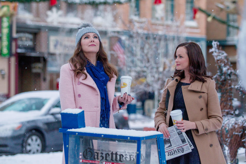 Lorelai and Rory standing outside with coffee cups, winter clothes, and snow in the background