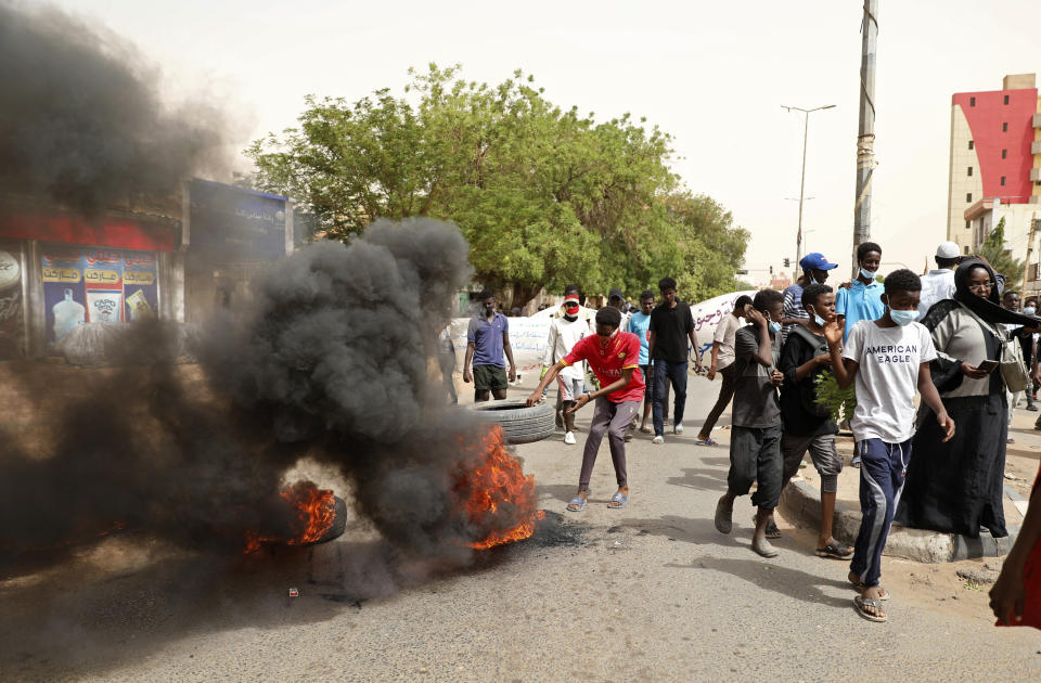 A man throws a tire on a fire during a protest over economic conditions, in Khartoum, Sudan, Wednesday, June 30, 2021. The World Bank and the International Monetary Fund said in a joint statement Tuesday, that Sudan has met the initial criteria for over $50 billion in foreign debt relief, another step for the East African nation to rejoin the international community after nearly three decades of isolation. (AP Photo/Marwan Ali)