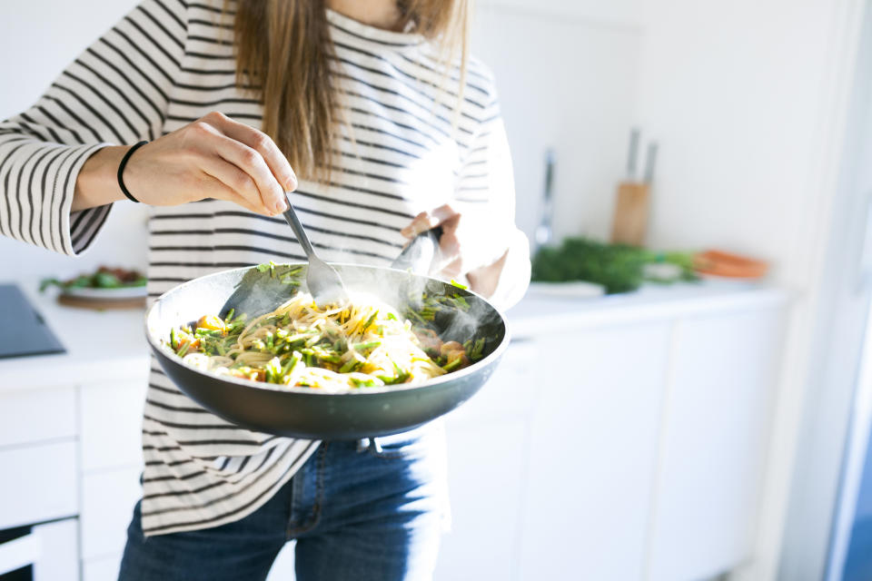 A woman cooking a stir-fry in a skillet