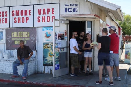 People buy goods at the front door of a liquor store after a powerful earthquake struck Southern California in the city of Ridgecrest