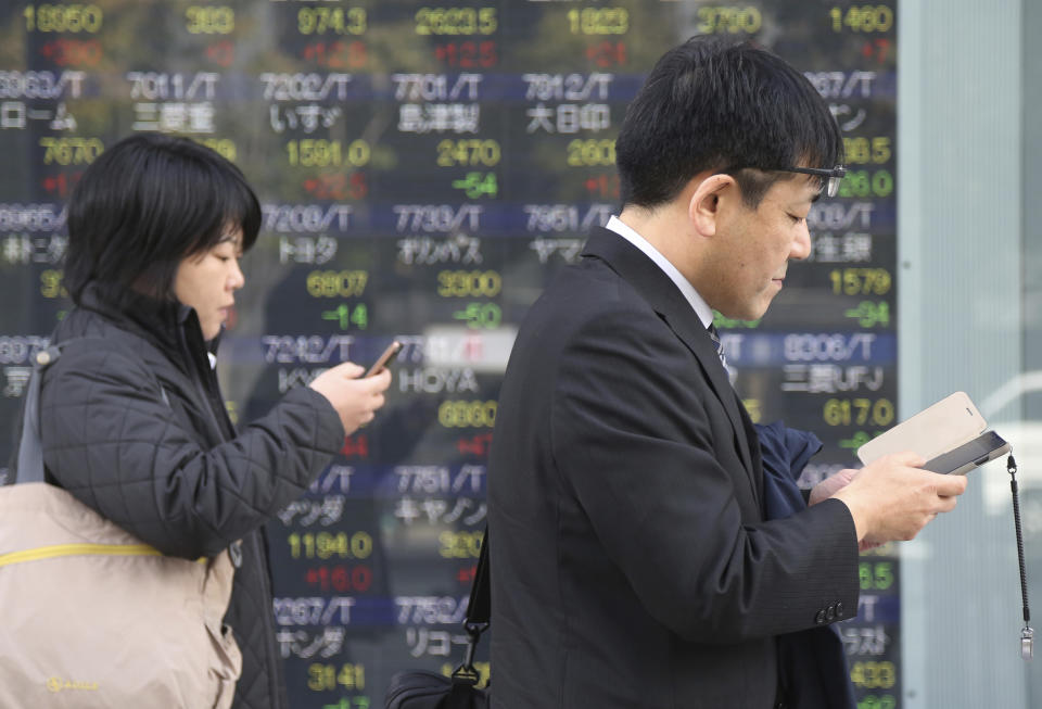 People look at their cell-phone in front of an electronic stock board of a securities firm in Tokyo, Monday, Nov. 26, 2018. Asian shares were mostly higher Monday on hopes that U.S. President Donald Trump and his Chinese counterpart Xi Jinping will unwind a blistering trade dispute at a meeting this week. (AP Photo/Koji Sasahara)