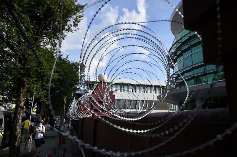 People walk next to barbwire at the Crown Property Bureau in Bangkok