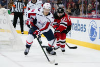 Washington Capitals' Lars Eller (20) and New Jersey Devils' Tomas Tatar (90) reach for the puck during the first period of an NHL hockey game Thursday, Oct. 21, 2021, in Newark, N.J. (AP Photo/Frank Franklin II)