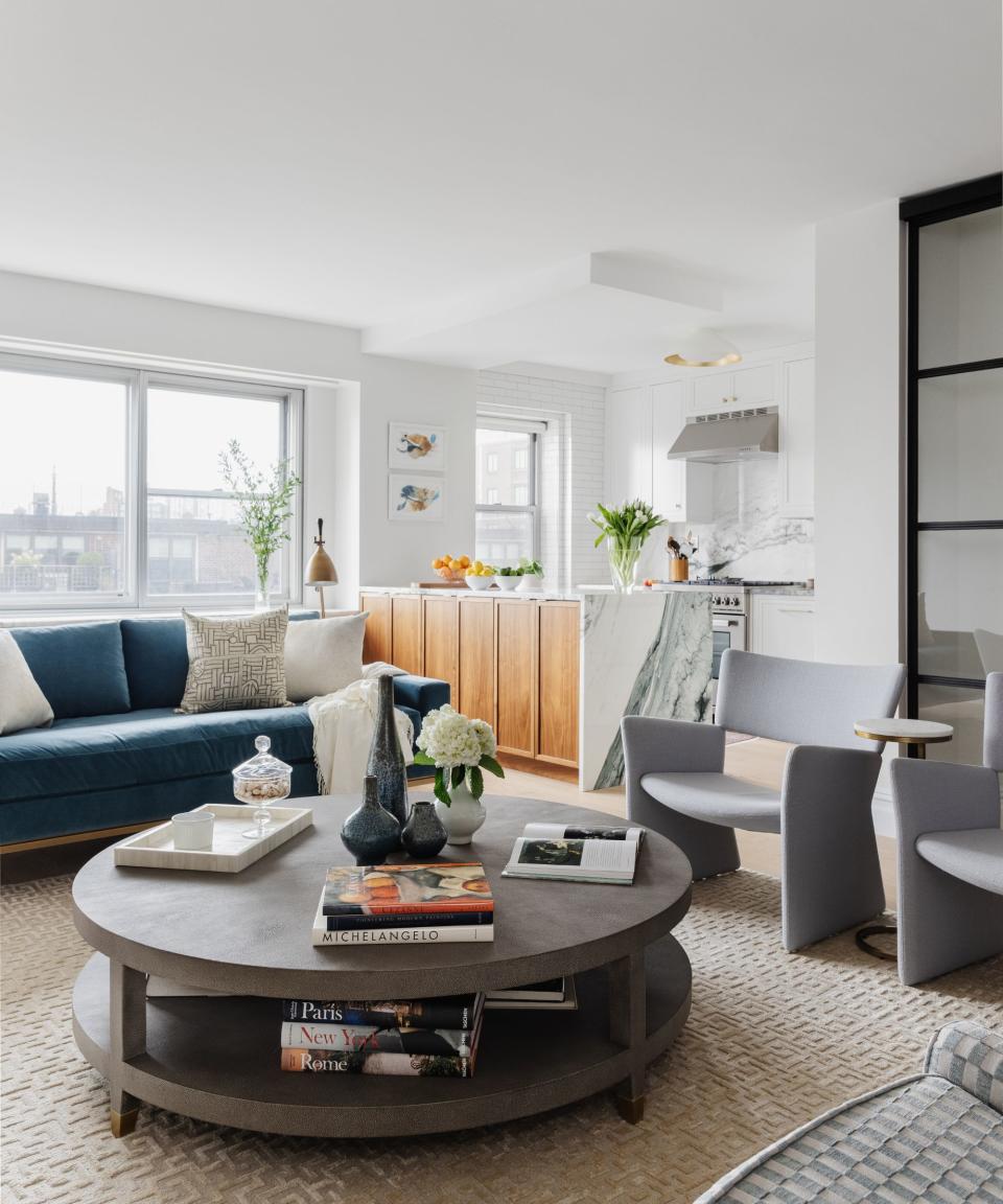 living room with round coffee table and blue sofa with white walls