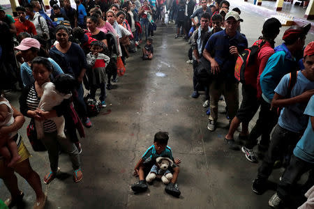 FILE PHOTO: A child sits on the floor among Honduran migrants, part of a caravan trying to reach the U.S., queue to get a mat to rest at a migrant shelter in Guatemala City, Guatemala October 17, 2018. REUTERS/Luis Echeverria/File Photo