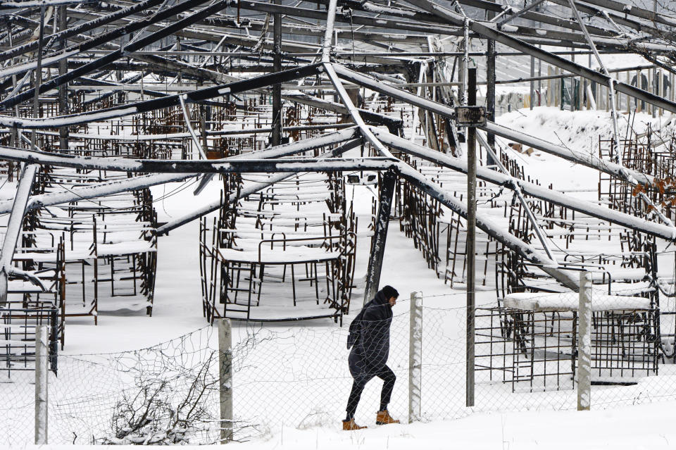 A migrant walks during a snowfall at the Lipa camp, outside Bihac, Bosnia, Monday, Jan. 11, 2021. Aid workers say migrants staying at a camp in northwestern Bosnia have complained or respiratory and skin diseases after spending days in make-shift tents and containers amid freezing weather and snow blizzards. Most of the hundreds of migrants at the Lipa facility near Bosnia's border with Croatia on Monday have been accommodated in heated military tents following days of uncertainty after a fire gutted most of the camp on Dec. 23. (AP Photo/Kemal Softic)