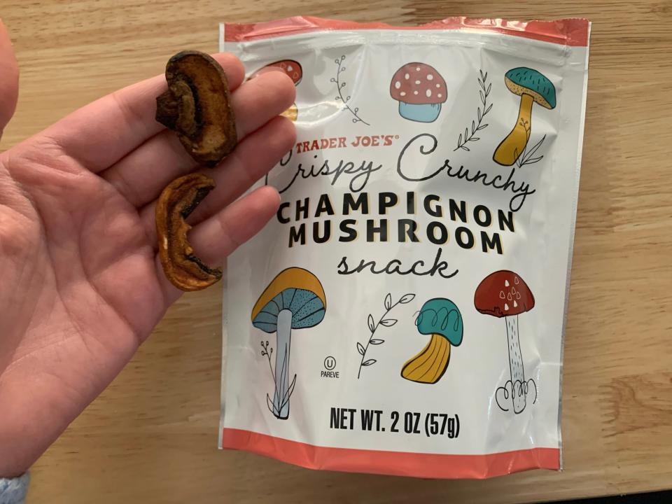 hand holding trader joe's mushroom snack beside white and pink bag