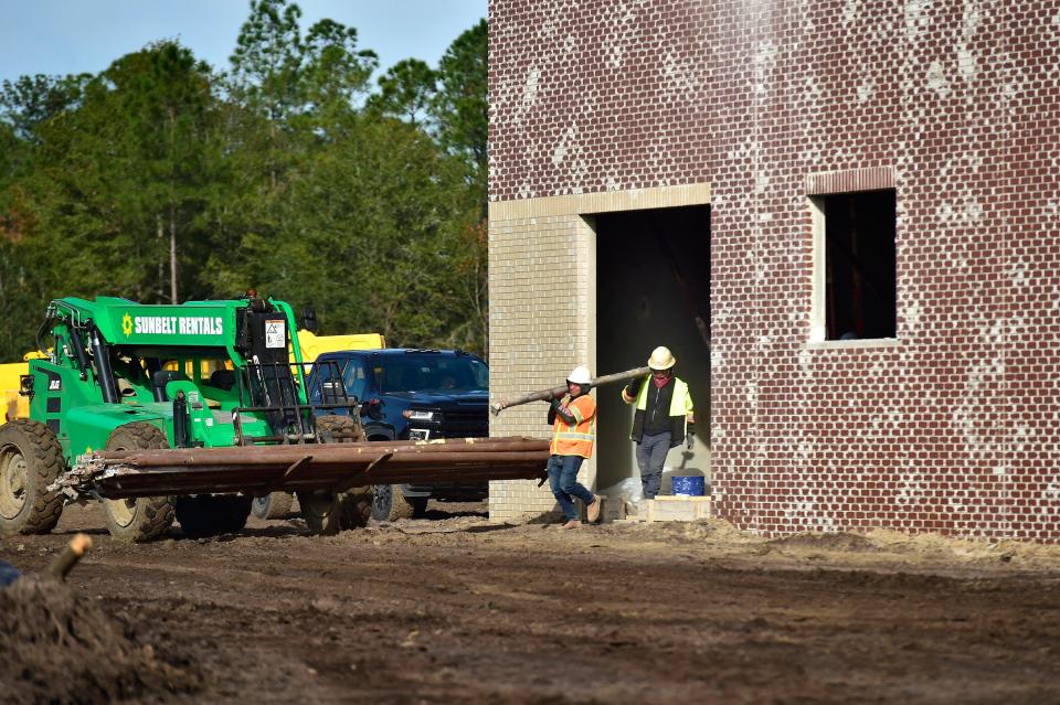 Workers remove construction support poles from part of the shell of what will become the new Chaffee Trail Middle School on Jacksonville's Westside. The school is scheduled to open in the summer.