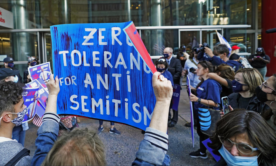 A woman holds a sign as she and others protest outside the offices of New York Gov. Andrew Cuomo, Thursday, Oct. 15, 2020, in New York. Three Rockland County Jewish congregations are suing New York state and Gov. Andrew Cuomo, saying he engaged in a "streak of anti-Semitic discrimination" with a recent crackdown on religious gatherings to reduce the state's coronavirus infection rate. (AP Photo/Kathy Willens)