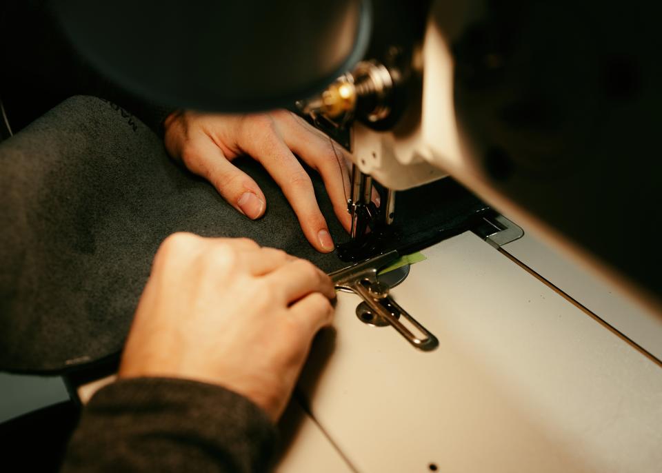 A McPherson College automotive restoration student works at a sewing machine for a class project.