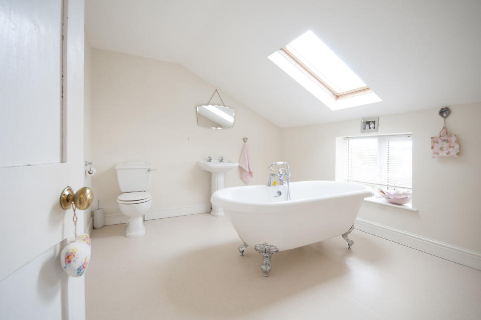 A general view of a bathroom with a white free standing roll top bath inside a home