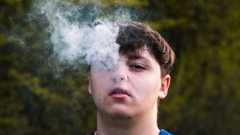 Male blowing vapor out of his face.