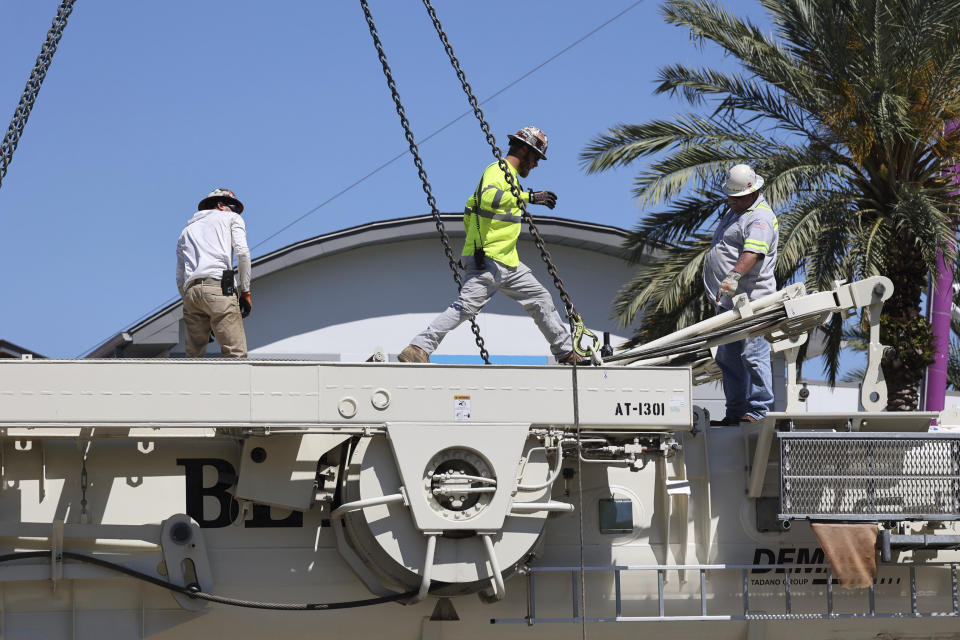 Work crews assemble the cranes that will be used to dismantle the Orlando FreeFall at ICON Park, on Tuesday, March 14, 2023 in Orlando, Fla. Almost a year after Tyre Sampson, a Missouri teen fell to his death, the 400-foot (122 meter) amusement ride was being dismantled this week in central Florida’s tourism corridor. (Ricardo Ramirez Buxeda/Orlando Sentinel via AP)