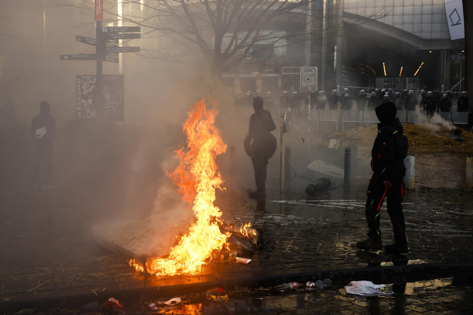People gather next to a burning mattress during a protest by farmers outside the European Parliament as European leaders meet for an EU summit in Brussels, Thursday, Feb. 1, 2024. European Union leaders meet in Brussels for a one day summit to discuss the revision of the Multiannual Financial Framework 2021-2027, including support for Ukraine. The graffiti reads in French: "You cannot make an omelet without burning tires". (AP Photo/Thomas Padilla)