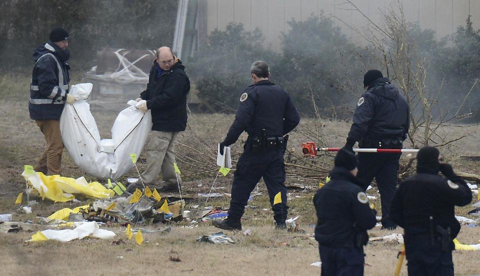 Investigators carry a body out from the crash site on Tuesday, Feb. 4, 2014 near Nashville. The small plane crashed on Monday, near a YMCA in suburban Nashville, killing everyone on board and damaging cars in the parking lot. (AP Photo/Mark Zaleski)