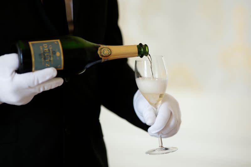 An employee serves a glass of Champagne during the traditional wine harvest at the Champagne house Deutz in Ay