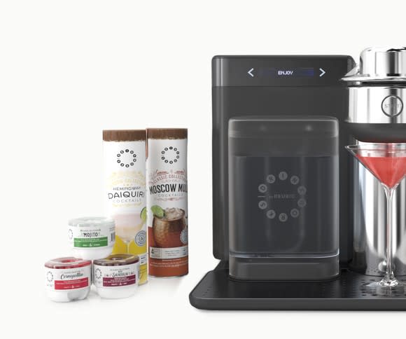 A Drinkworks Home Bar by Keurig with various cocktail mixes on the side.