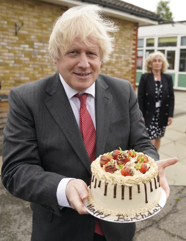 Boris Johnson holds up a birthday cake - baked for him by school staff - during a visit to Bovingdon Primary Academy. The Prime Minister is facing fresh allegations of breaking coronavirus rules after it emerged that a gathering to wish him a happy birthday was held inside No 10 during the first lockdown. (Photo: Andrew Parsons / Downing Street via PA Media)