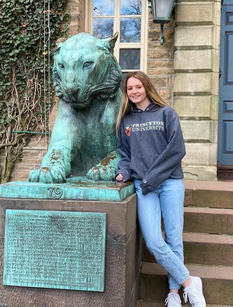 Shea Burke stands next to a tiger statue on Princeton University's campus