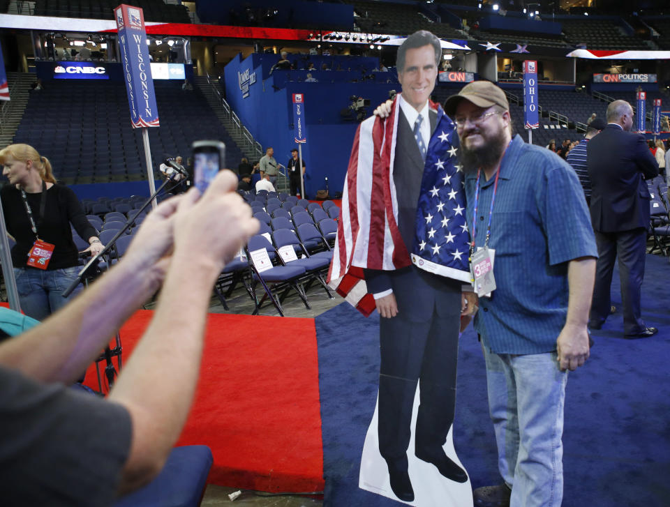 Travis Chapin from St. Petersburg, Fla., poses for a picture with a life-size picture figure of Republican presidential nominee Mitt Romney on the floor at the Republican National Convention in Tampa, Fla., on Wednesday, Aug. 29, 2012. (AP Photo/Jae C. Hong)