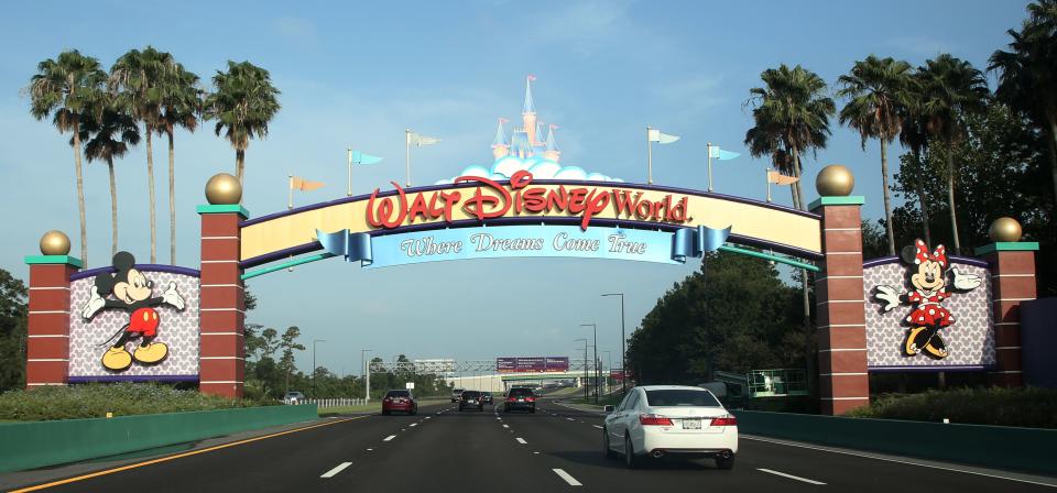 Les visiteurs passent devant un panneau les accueillant à Walt Disney World le premier jour de la réouverture de l'emblématique parc à thème Magic Kingdom à Orlando, en Floride, le 11 juillet 2020.