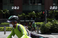 Food delivery cyclists wearing protective face masks move along the Orchard Road shopping belt in Singapore, Friday, April 10, 2020. The Singapore government put in place "circuit breaker" measures in the light of a sharp increase of COVID-19 cases in recent days. Under the measures which will last through May 4, people have to stay home and step out only for essential tasks, such as going to work if they are in essential services, buying food and groceries, or for a short bout of exercise. (AP Photo/Yong Teck Lim)