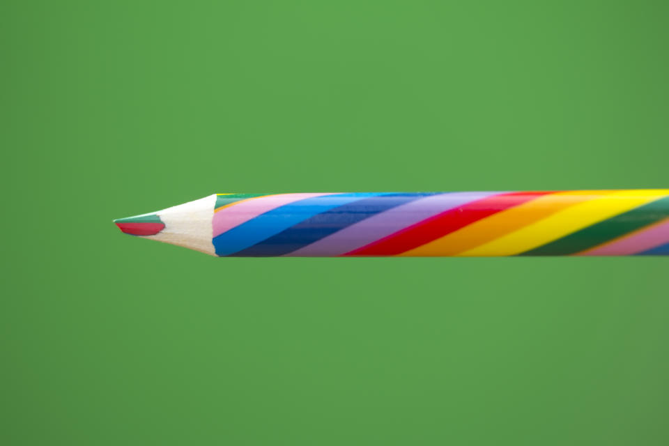 Image of a multicolored pencil on a green background.