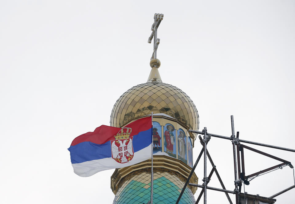 In this photo taken Friday, Jan. 11, 2019, the Serbian flag flies near a new church under construction designed in the Russian style in the village Banstol in northwestern Serbia. Topped with Russia-style green and gold onion-shaped domes, the church in this tiny village in northwestern Serbia is still under construction but it has already been dubbed ''Putin's church.'' (AP Photo/Darko Vojinovic)