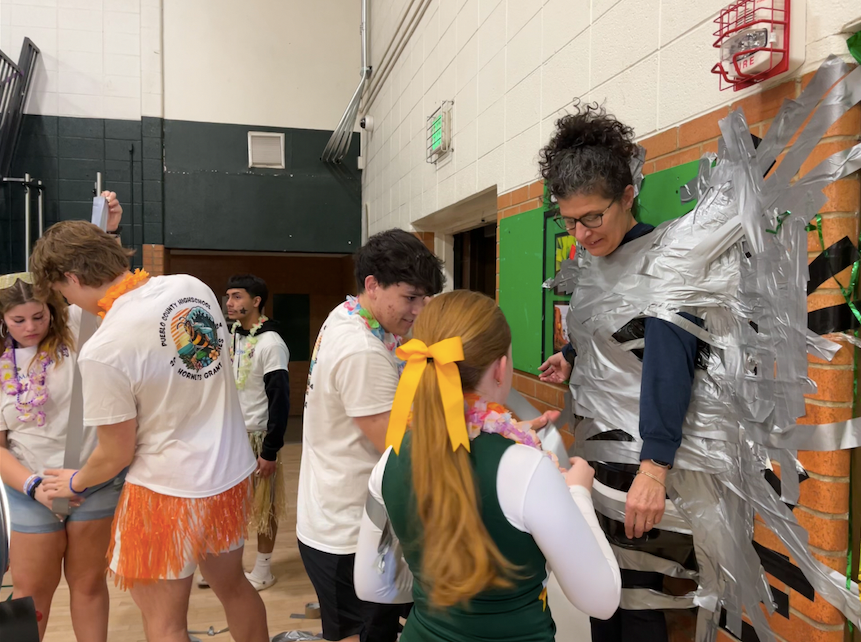 Pueblo County High School students Tori Eyestone, Evan Budd, Niko Cozzetto and Kelly Sloan duct tape science teacher Suzan Selle to the gymnasium wall to raise funds for Make-A-Wish Colorado.