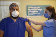 FILE - In this Oct. 9, 2020 file photo, a health worker administers the first dose of a COVID-19 vaccine currently on phase III clinical trials to Cem Gun, an Emergency Medicine Physician, at the Acibadem Hospital in Istanbul, Friday, Oct. 9, 2020. Turkish health minister Fahrettin Koca, who had previously announced an agreement with Chinese biopharmaceutical company Sinovac Biotech for 50 million doses of CoronaVac, said in a statement late Wednesday, Dec. 2, 2020, that the first shipment of the inactivated vaccine will arrive in Turkey after Dec. 11. (AP Photo/Emrah Gurel, file)