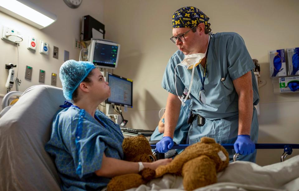 Amedy Dewey, left, sits on a hospital bed as Dr. Christian Vercler, plastic surgeon, goes through a facial exercise before her facial reconstruction surgery at the University of Michigan C.S. Mott Children's Hospital in Ann Arbor on Monday, July 24, 2023.