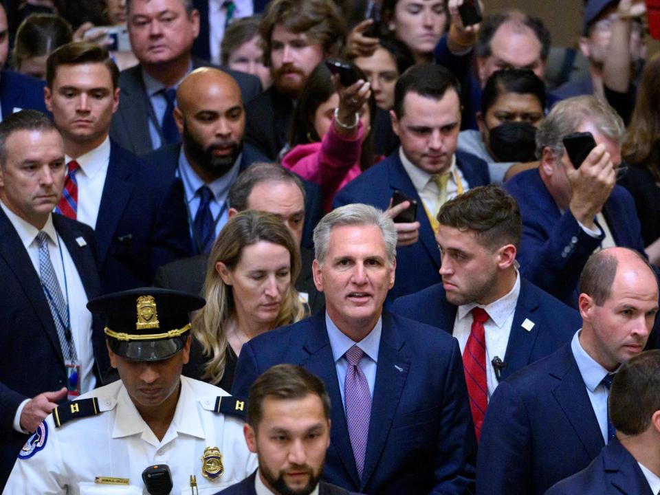 Kevin McCarthy walks from the House Chamber, followed by a large group behind him.