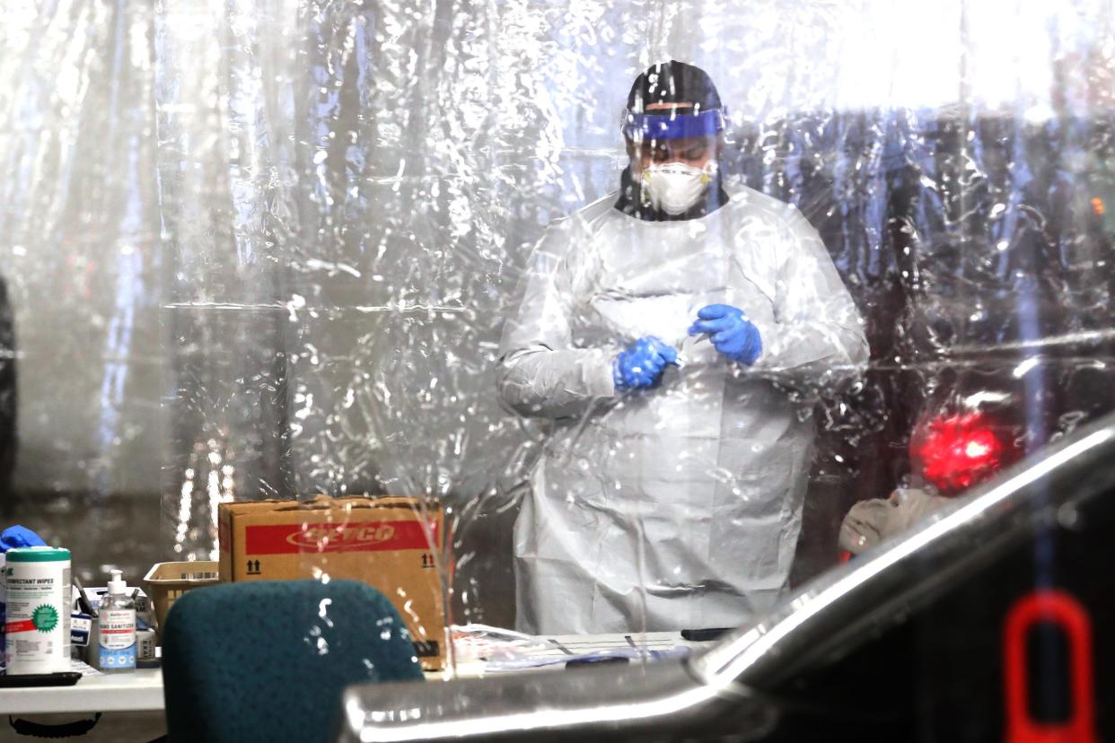 A public health worker administers drive-up coronavirus tests Dec. 28, 2021, at the Northwest Health Center COVID-19 Vaccination Site in Milwaukee.